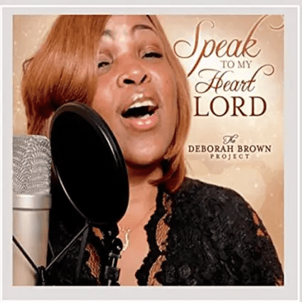 A woman singing into a microphone with the words speak to my heart lord