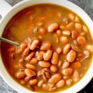 A bowl of beans and soup with a spoon.