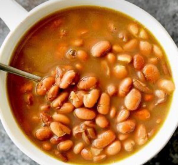 A bowl of beans and soup with a spoon.