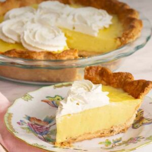 A pie with whipped cream on top sitting next to another pie.