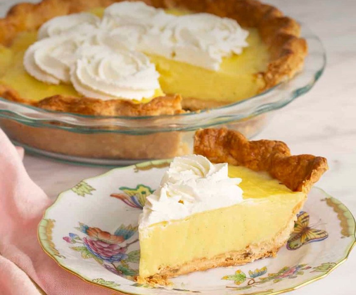 A pie with whipped cream on top sitting next to another pie.