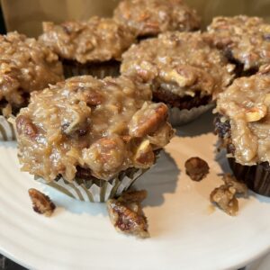 A white plate topped with several muffins covered in nuts.