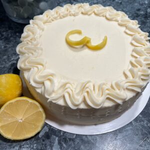 A cake with white frosting and lemon slices on top.