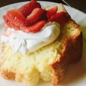 A piece of cake with whipped cream and strawberries on top.