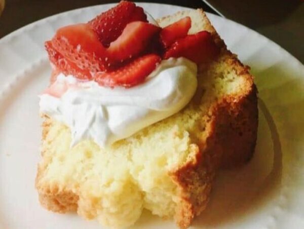 A piece of cake with whipped cream and strawberries on top.