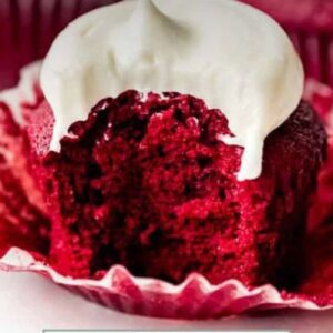 A red velvet cupcake with white frosting on top.