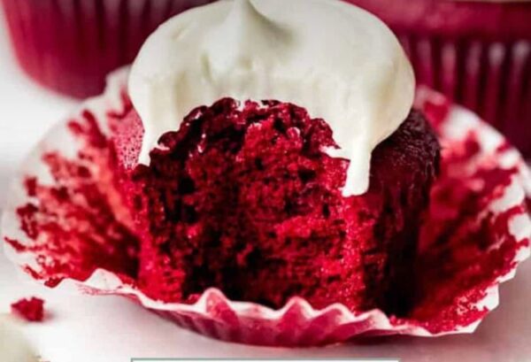 A red velvet cupcake with white frosting on top.