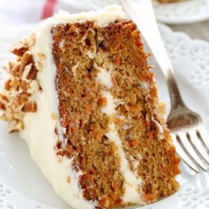 A piece of carrot cake with white frosting on top.