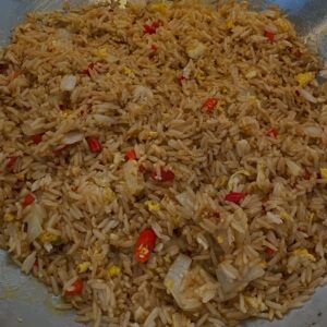 A bowl of rice with meat and peppers.