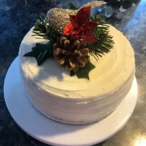 A white cake with pine cones and christmas decorations on top.