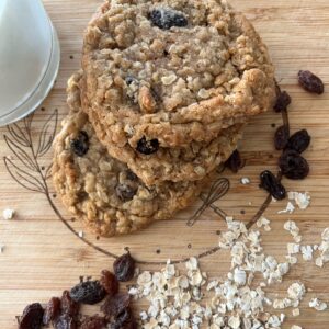 A wooden table with oatmeal cookies and raisins.