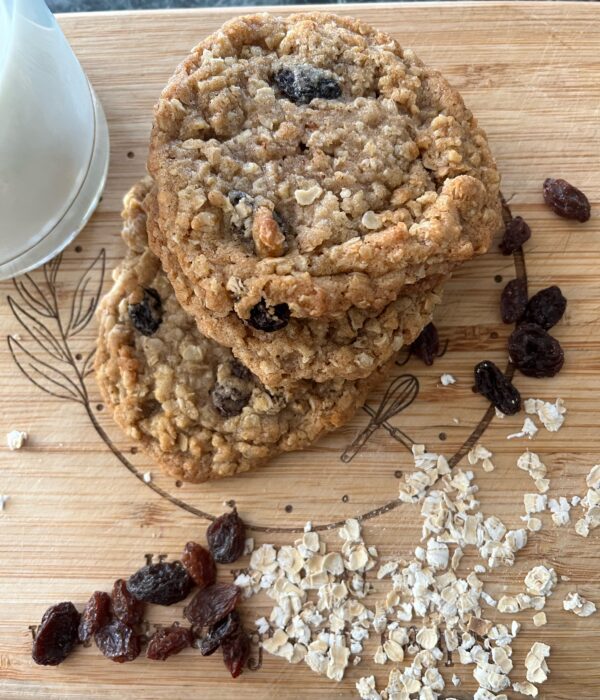 A wooden table with oatmeal cookies and raisins.