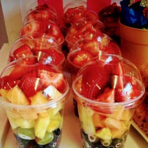 A table with several cups of fruit on it.