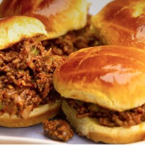 A plate of sandwiches with meat and buns.