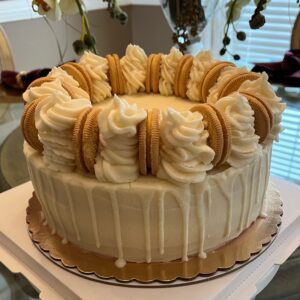 A cake with white frosting and cookies on top.