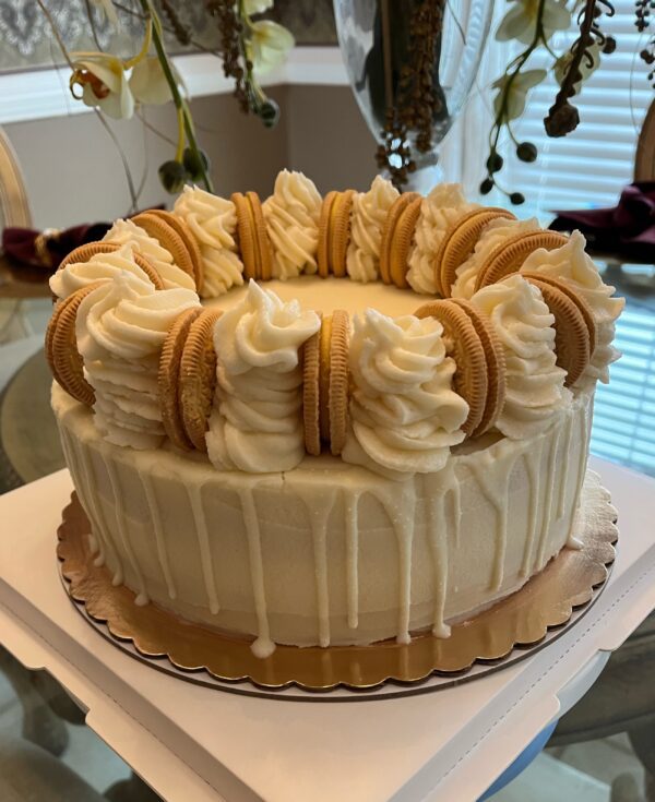 A cake with white frosting and cookies on top.