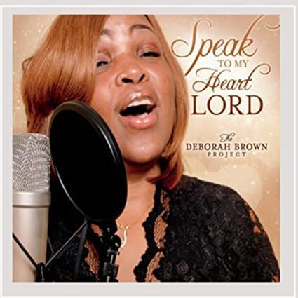 A woman singing into a microphone with the words " speak to my heart lord " in front of her.